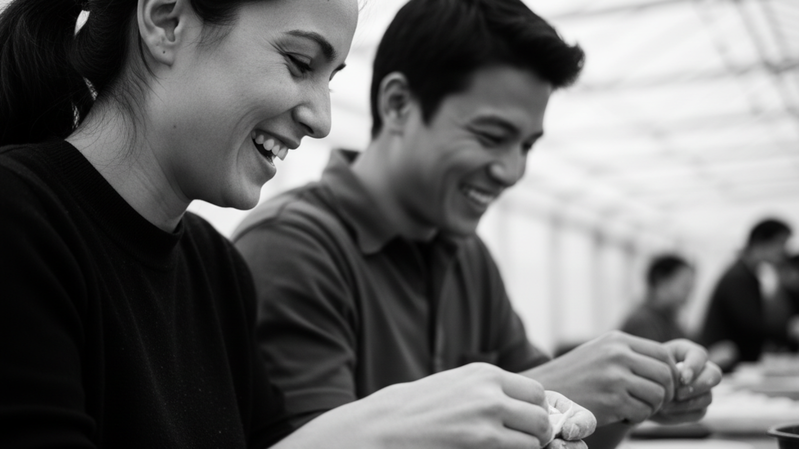 Two people sitting together, possibly at a table, with a blurred background.